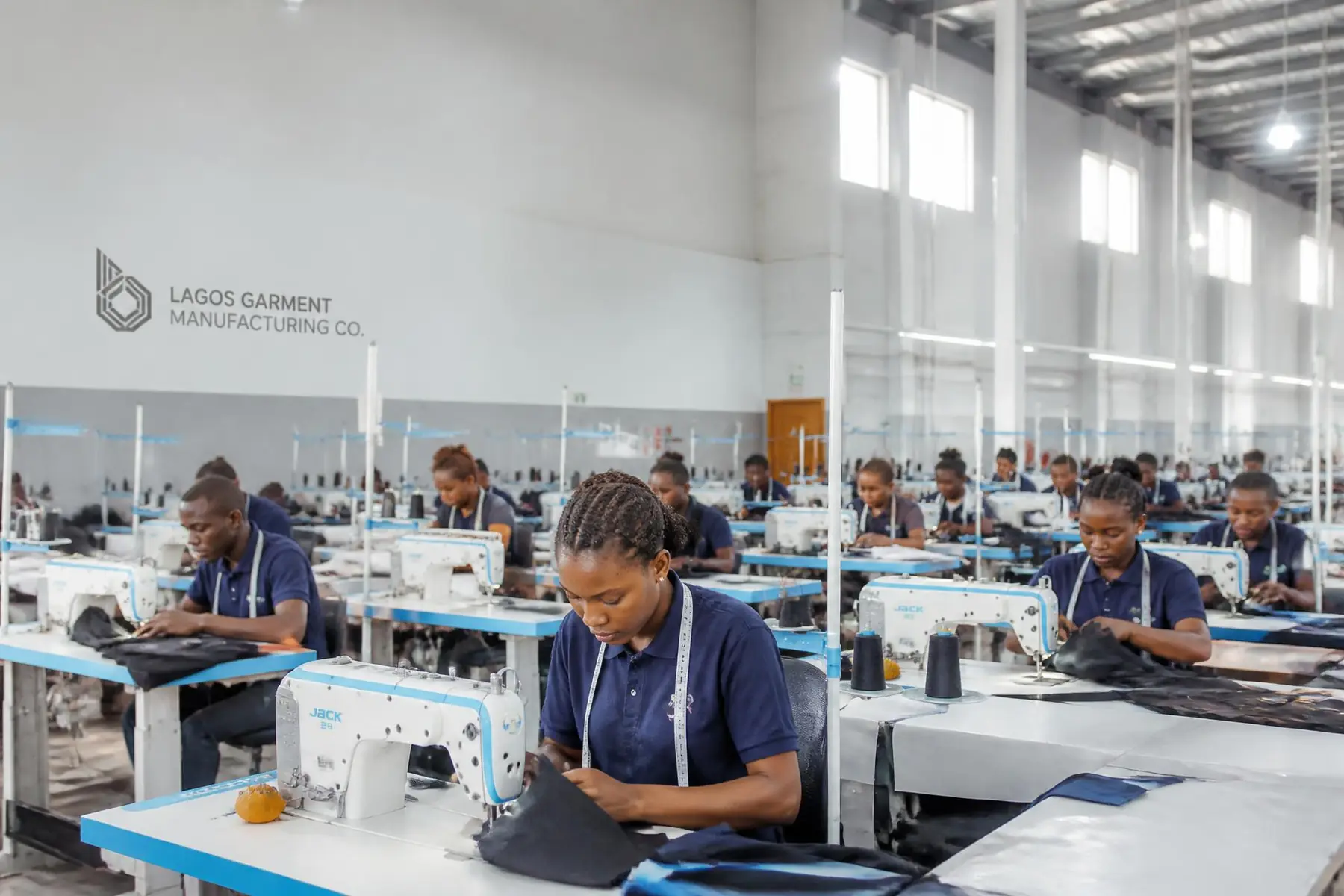 Operators at industrial sewing machines on the Oyertur garment production floor in Lagos
